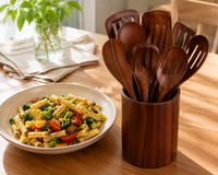 Plato de pasta con verduras junto al set de teca en su portautensilios de regalo